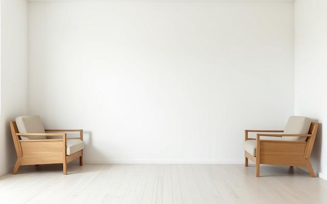 家具が少なく、殺風景なリビングルーム。白い壁と簡素な木製家具が置かれている